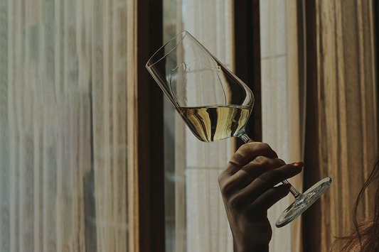 Examen visuel d'un vin, verre incliné sur fond blanc 